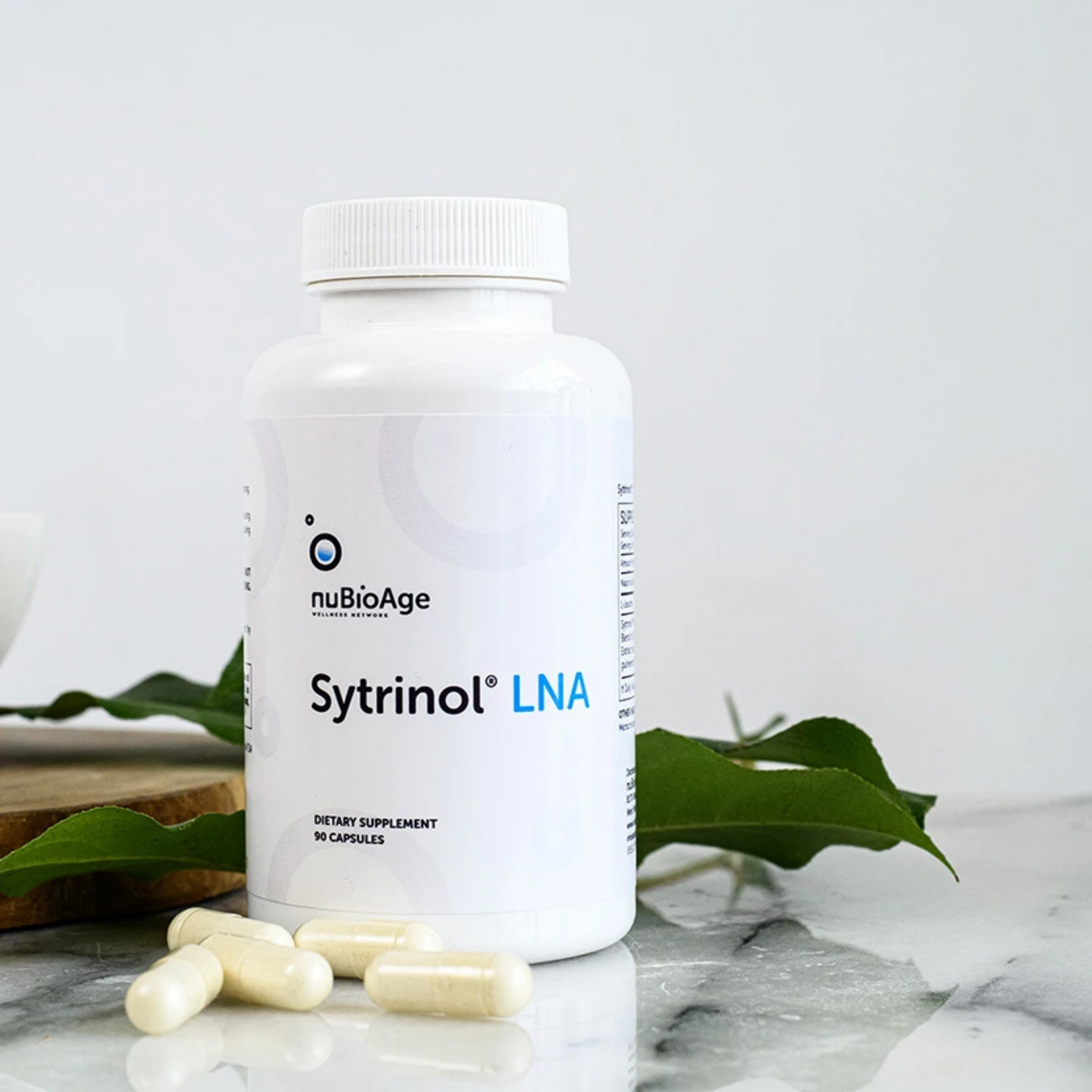 Sytrinol LNA by nuBioAge dietary supplement bottle with capsules on marble surface and green leaves background